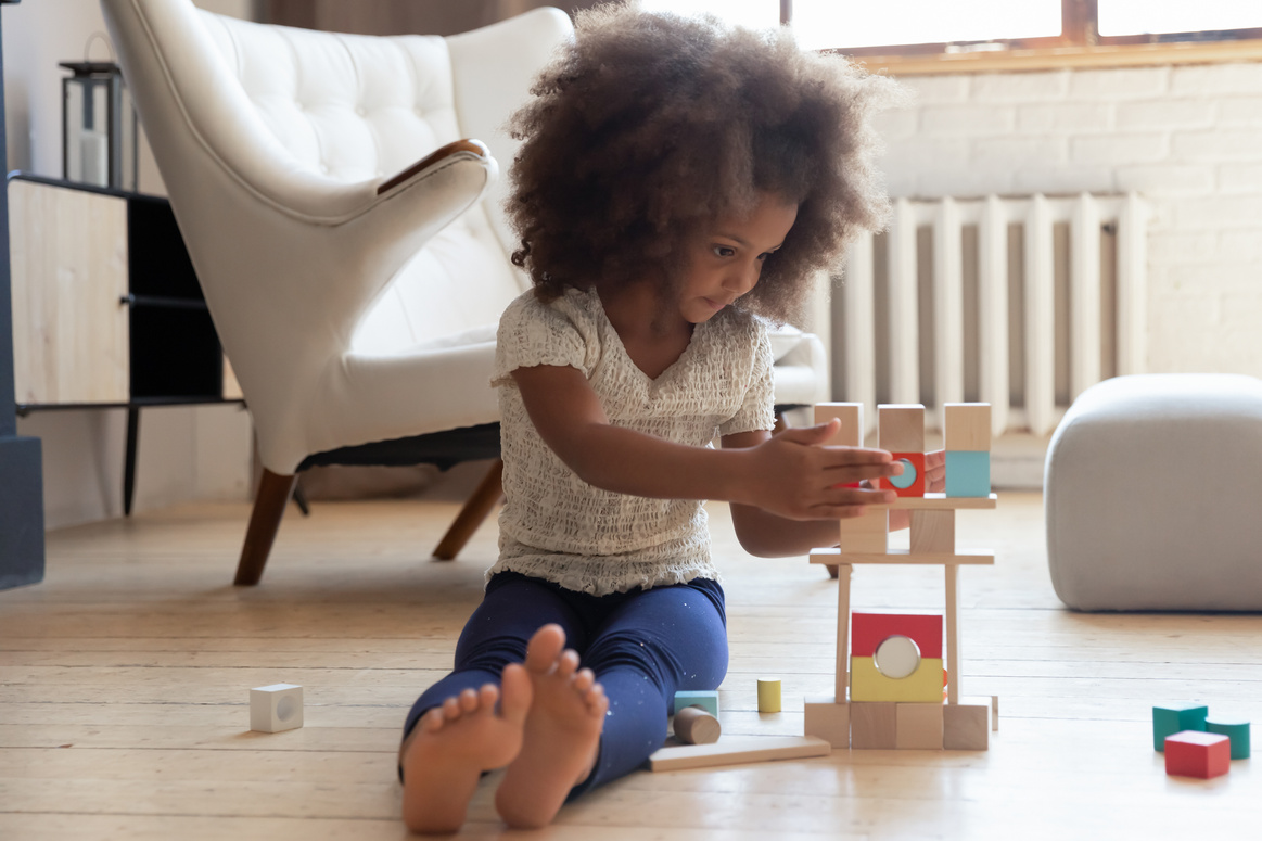 Focused adorable little biracial child playing alone at home.